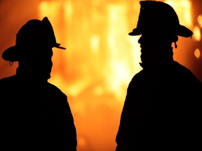 צל של שני כבאים על רקע שריפה